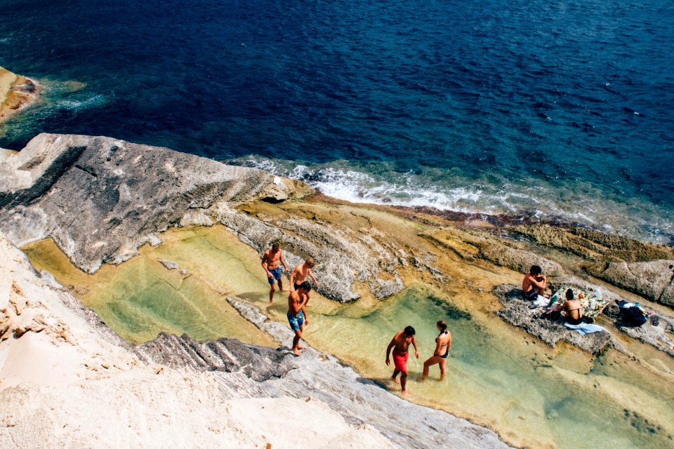 People Relaxing On Rocky Beach