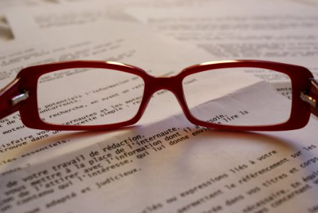 Red Framed Eyeglass On Top Of Paper photo