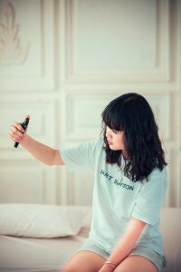 Girl In Blue Crew Neck Shirt Using Her Mobile Phone Indoors photo