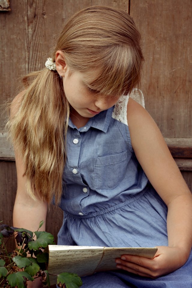 Portrait Of Young Girl Reading Outdoors