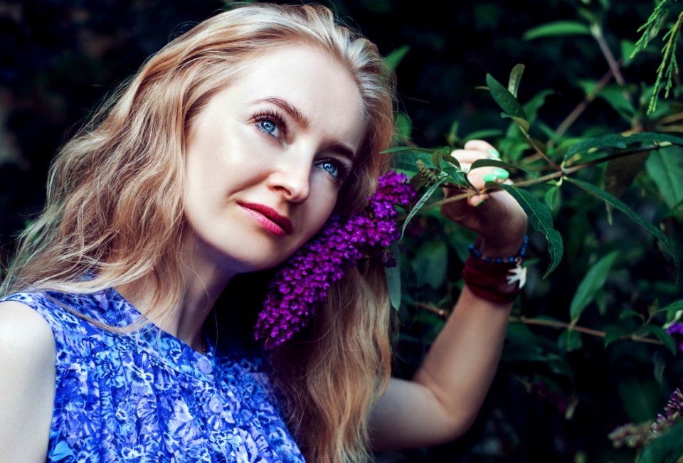 Woman Wearing Blue Floral Sleeveless Dress Smelling Violet Flower