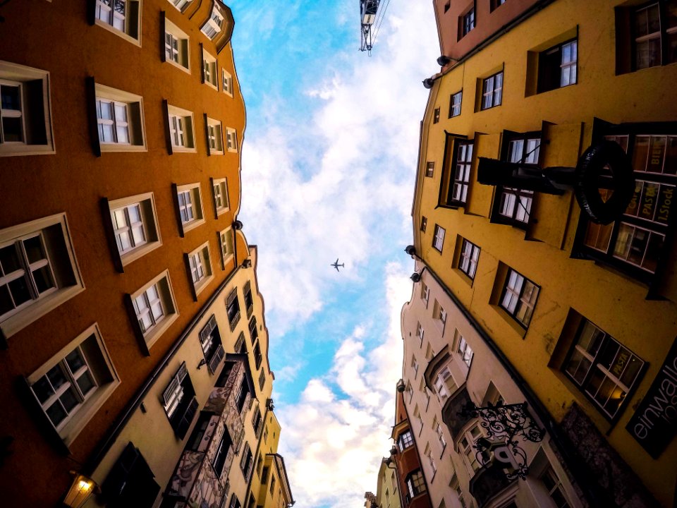 Airplane In Sky Between Buildings