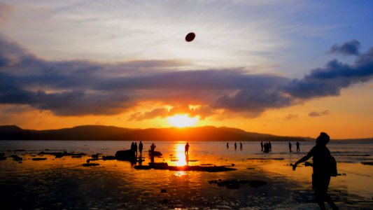 People Playing On Beach At Sunset photo