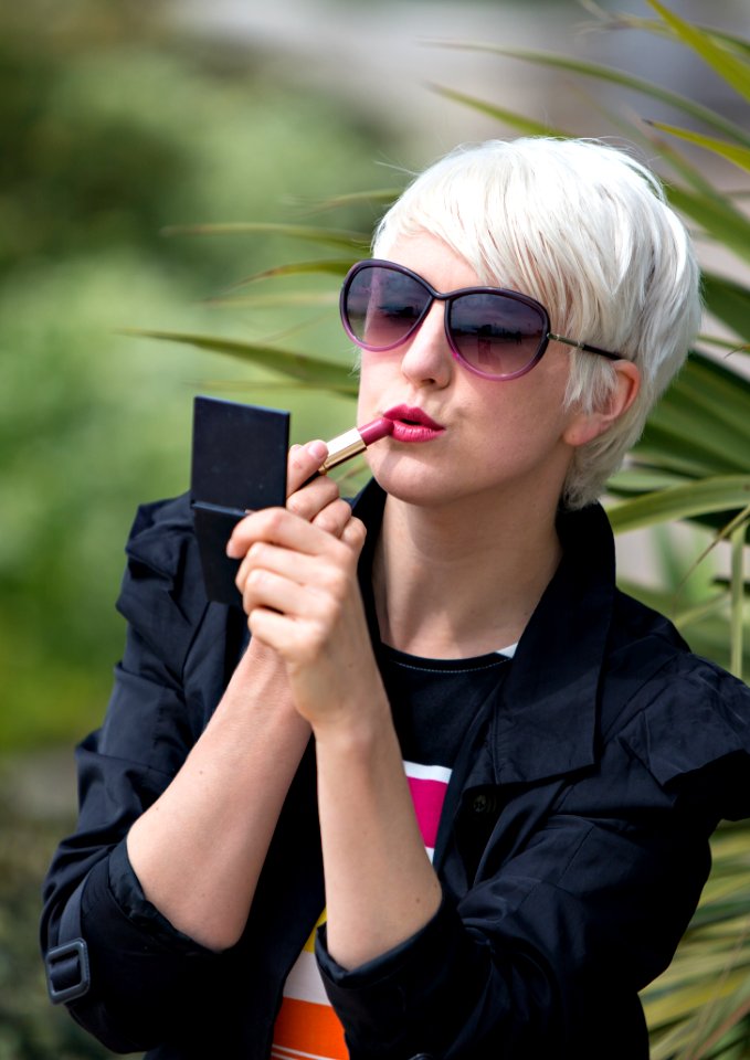 Blond Short Haired Woman Applying Pink Lipstick Outside