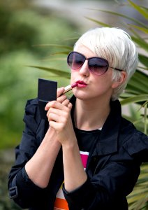 Blond Short Haired Woman Applying Pink Lipstick Outside