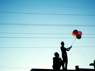 Men Holding Red Pink And Yellow Balloon Under Blue Sky During Daytime photo