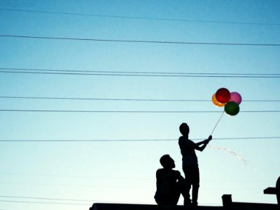 Men Holding Red Pink And Yellow Balloon Under Blue Sky During Daytime