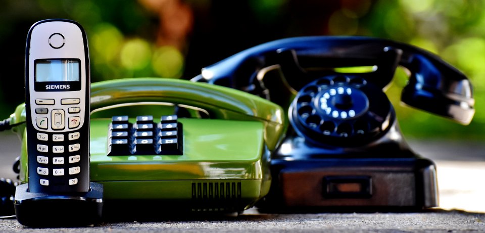Black And Green Rotary Telephones Beside Cordless Home Telephone