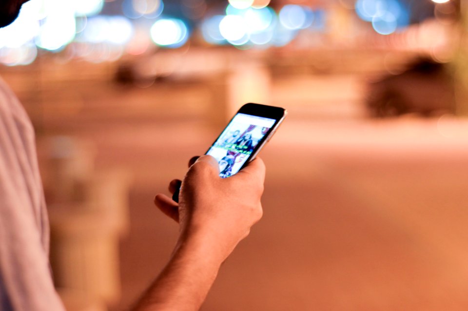 Man Holding And Scrolling A Black Smartphone