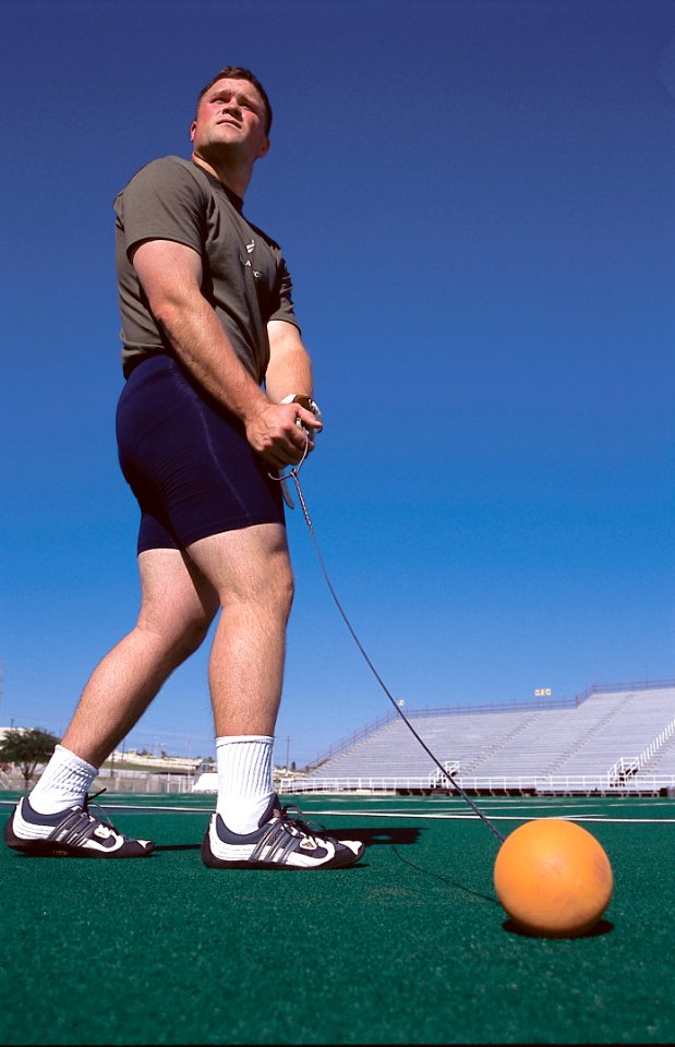 Man Wearing Grey Shirt Swinging Orange Ball
