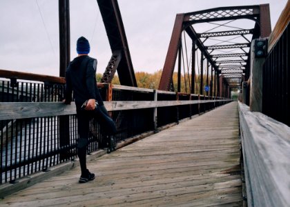 Man Stretching Leg On Footbridge