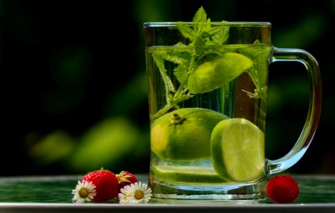 Green Round Fruit On Clear Glass Mug With Water photo
