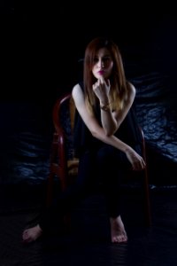 Woman Sitting On Brown Chair With Black Background
