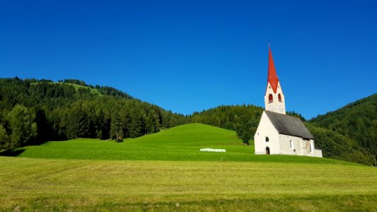 White Gray And Red Chapel On Green Field During Clear Sky Day Time