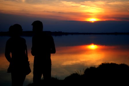 Silhouette Of Man And Woman Near Water During Sun Set photo