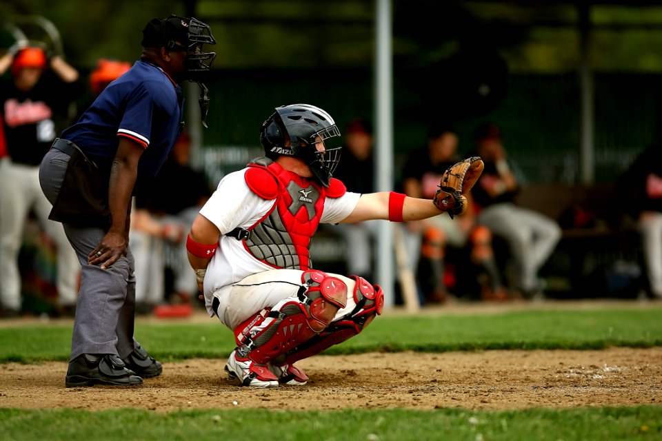 White And Red Baseball Player With Black Face Helmet And Brown Leather Mitts