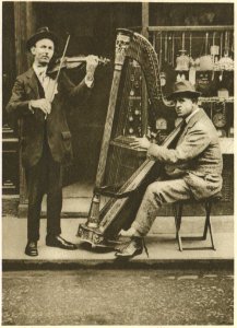 The Strains Of The Itinerant Harpist Come Through The Din Of Traffic