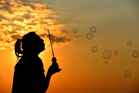 Girl Blowing Bubbles At Sunset photo