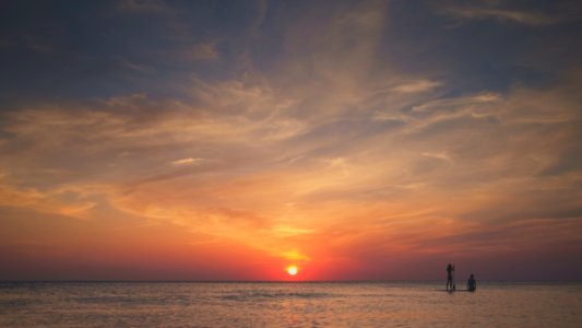 Surfers In Ocean At Sunset