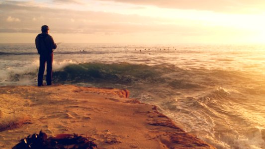 Man Fishing On Sandy Shore By Ocean