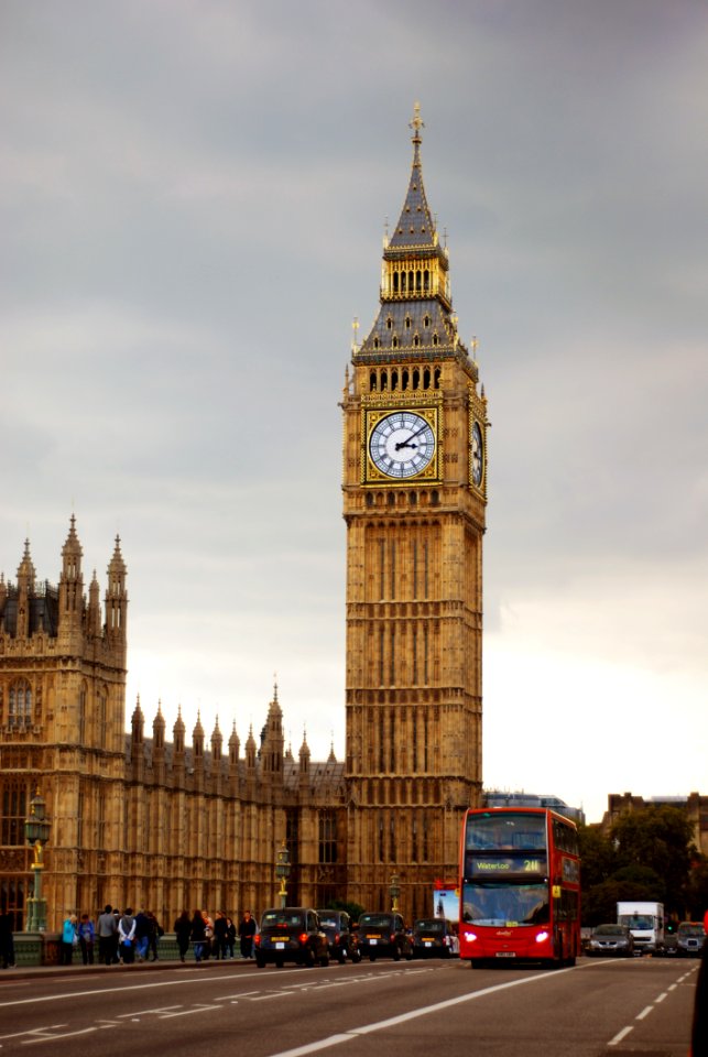 Big Ben Tower Near City Road With Bus And Cars Traveling Under Gray White Clouds