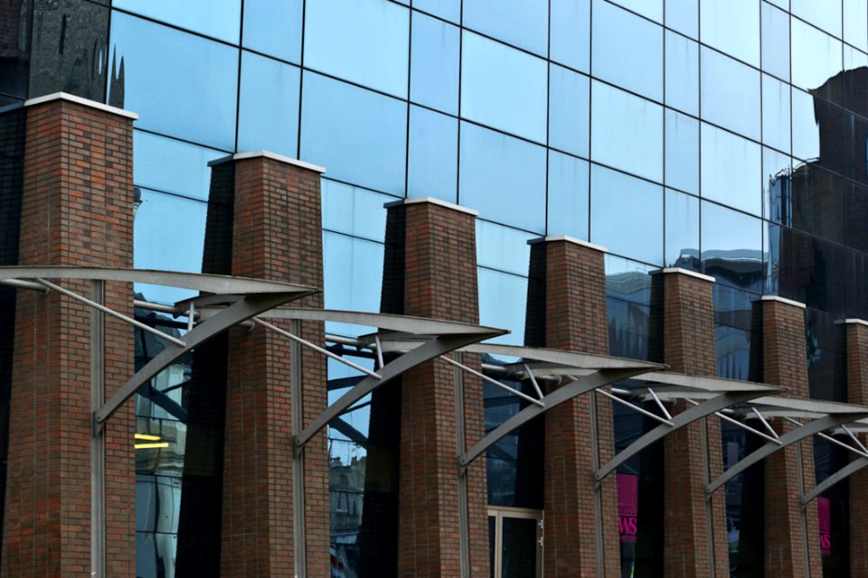 Glass And Steel Facade Of A Modern Hotel Reflecting Old City Elements