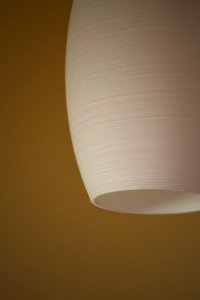 White Ceramic Ceiling Lamp Against Mustard Colored Wall photo