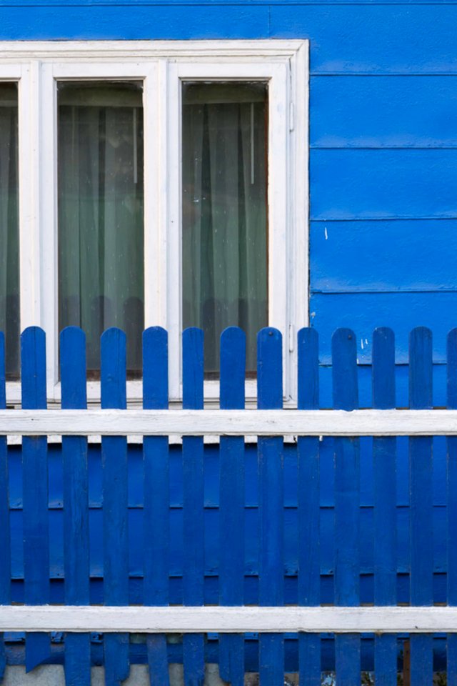 Country Home Painted In Blue With White Window Frames And Matching Fence