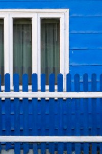 Country Home Painted In Blue With White Window Frames And Matching Fence