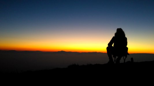 Silhouette Of Person On Mountain At Sunset photo