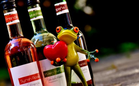 Green Frog With Red Heart Figurine Beside Glass Bottles photo