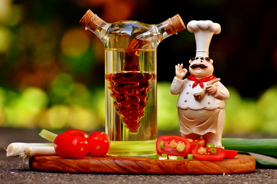 Chef Figurine Beside Clear Glass Bottle And Tomatoes photo