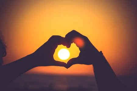 Two Hands Making A Heart With Sunset In Background photo