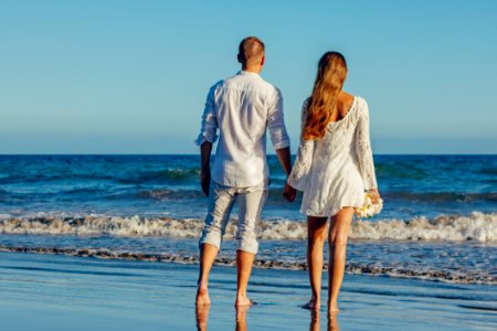 Rear View Of Couple On Beach Against Clear Sky photo
