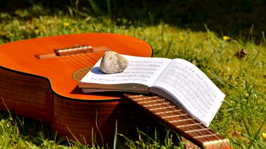 Song Book On Brown Classical Guitar On Green Grass During Daytime photo