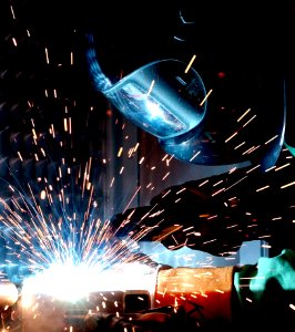 Person In Welding Mask While Welding A Metal Bar photo