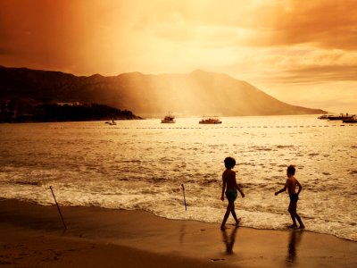 Children On Beach With Boats In Water