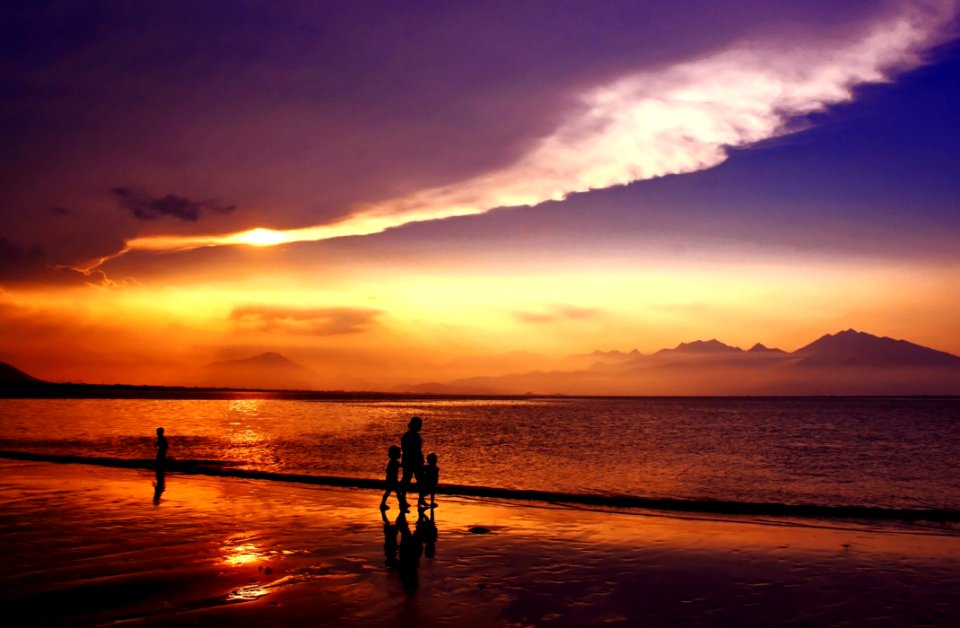 Silhouette Of People Walking On Seashore Under Gray And White Clouds During Daytime