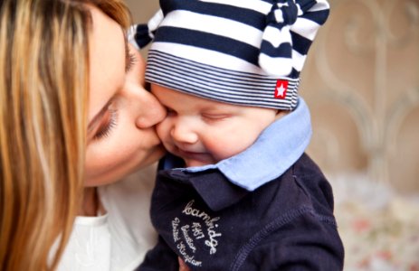 Woman In White Shirt Kissing Baby With Black And White Stripe Knit Cap photo