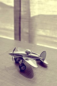 Sepia Photography Of Stainless Steel Biplane On Brown Wooden Table Near Window During Daytime