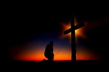 Man Kneeling In Front Of Cross photo