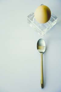 Stainless Steel Spoon Beside Yellow Egg On Clear Glass Fragment photo
