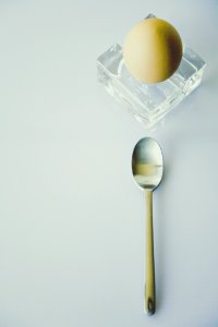 Stainless Steel Spoon Beside Yellow Egg On Clear Glass Fragment