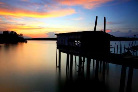 Silhouette Of House On Top Of Ocean Water During Sunset