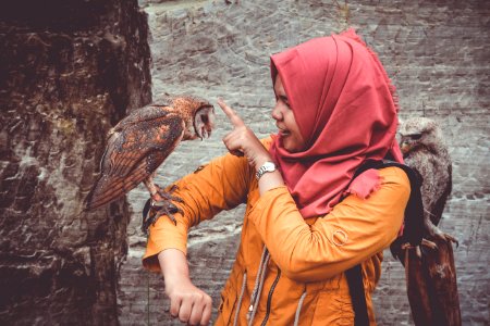 Woman In Red Hijab And Orange Coat Touching Brown And White Owl