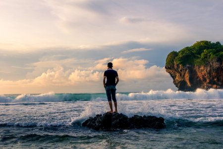 Man Standing On Stone Near Seashore During Sunrise Photography photo