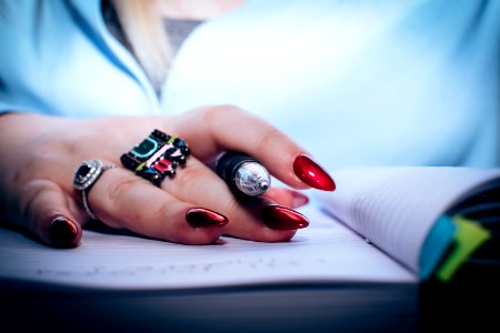 Person With Red Nail Polish Holding Black Pen photo