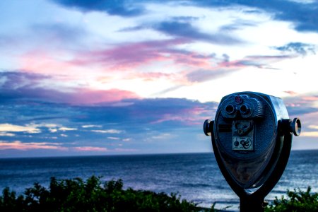 Gray And Black Tower Viewer Near Green Grass Field And Beach Under Blue White And Gray Clouds