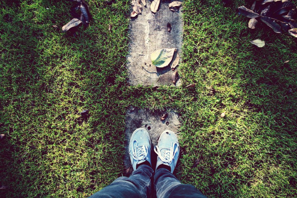 Person Standing On Gray Stone Surrounded By Green Grass During Daytime