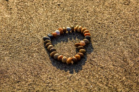 Brown And Grey Stone Formed Heart On Sand photo